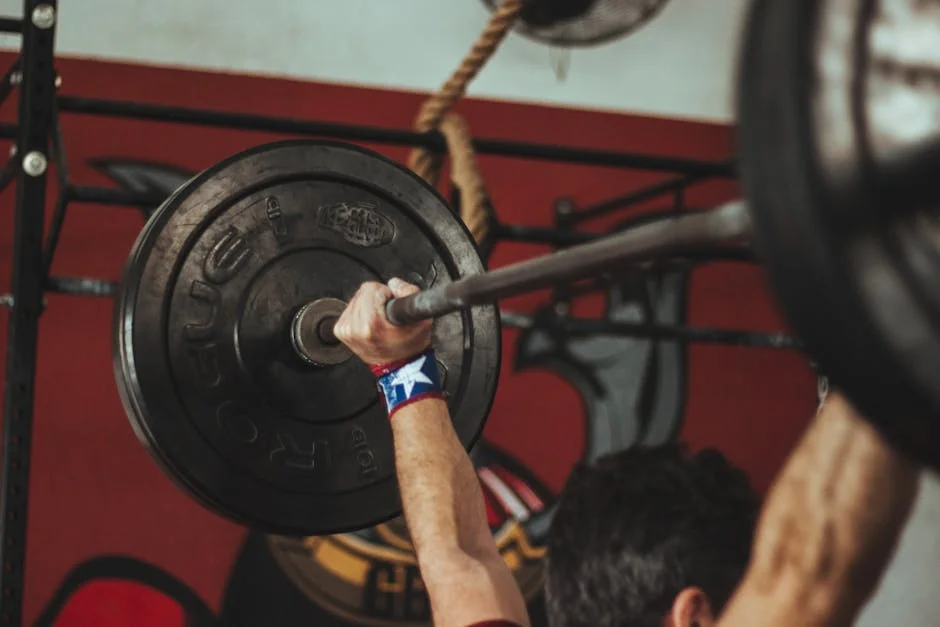 Athlete lifting heavy barbell during strength training session in gym. - exercise workout gym - New year resolution fitness gear promo codes