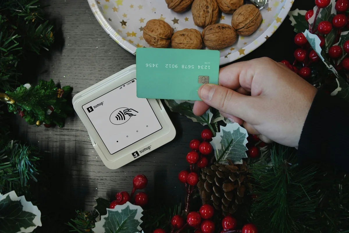 A close-up of a SumUp card reader and a green card, beautifully styled with Christmas-themed decor, creating a warm holiday shopping vibe. - redeemable gift card codes for online retailers
