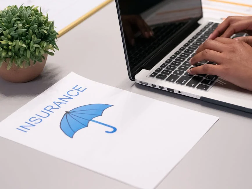 Close-up of hands typing on laptop with an insurance document visible on the desk. - financial protection document - Save money on car insurance with exclusive codes