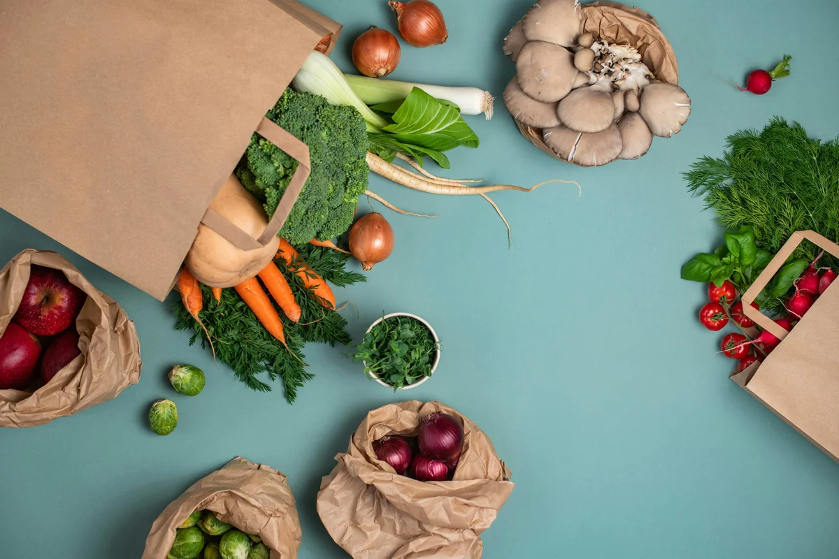 a table topped with bags filled with different types of vegetables - how to save money on organic groceries with coupons