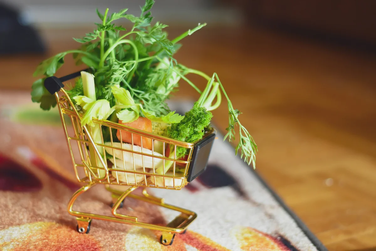 green leaves on shopping cart - how to save money on organic groceries with coupons
