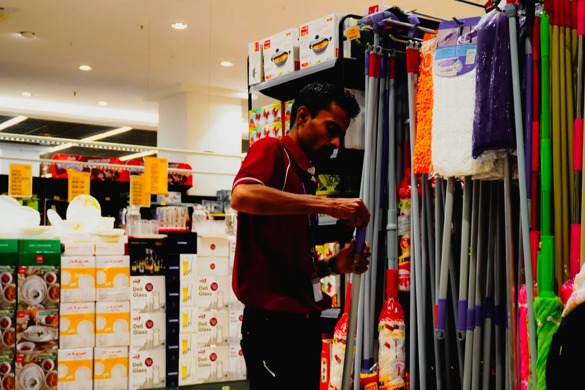 Man arranging cleaning supplies in a store - spring cleaning supply coupons and household deals