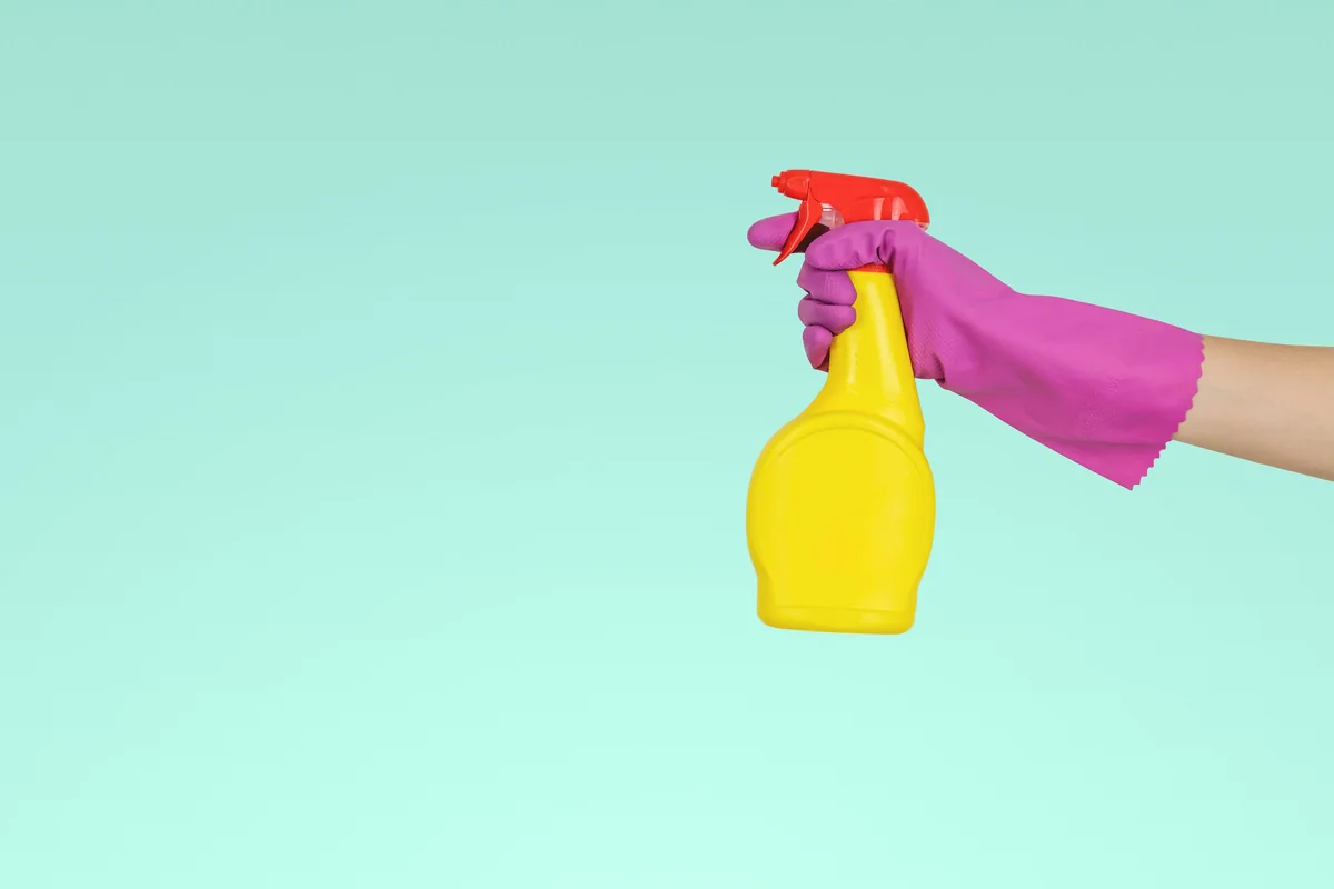 person holding yellow plastic spray bottle - spring cleaning supply coupons and household deals