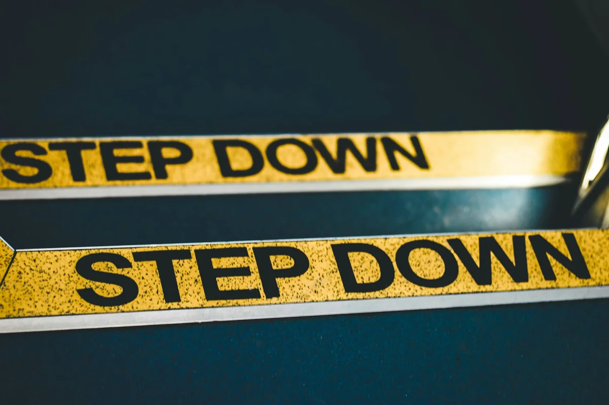 a close up of a pair of scissors near a step down sign - step by step guide to extreme couponing for beginners