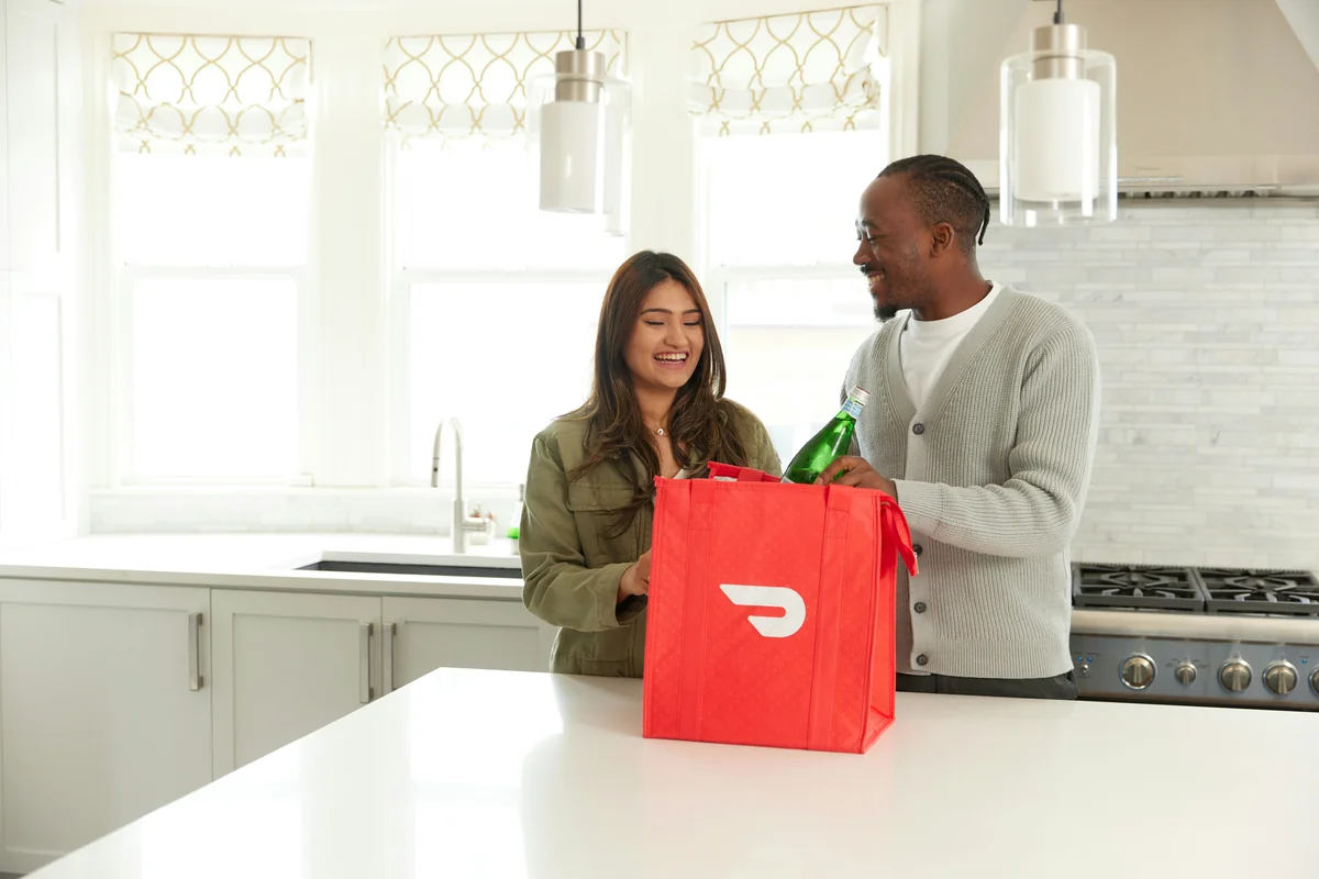 a man and woman standing in a kitchen with a red bag - top rated meal kit delivery service discounts