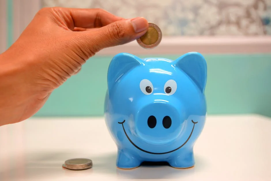 Hand inserting a coin into a blue piggy bank for savings and money management. - piggy bank money - How to use digital coupons at checkout for savings