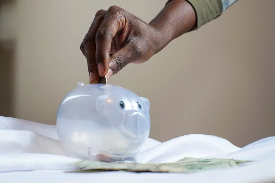 Close-up of a person's hand placing coins into a transparent piggy bank to save money. - piggy bank money - How to use digital coupons at checkout for savings