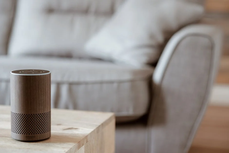A modern smart speaker sits on a wooden table in a cozy, minimalist living room setting. - verified amazon promo codes for electronics
