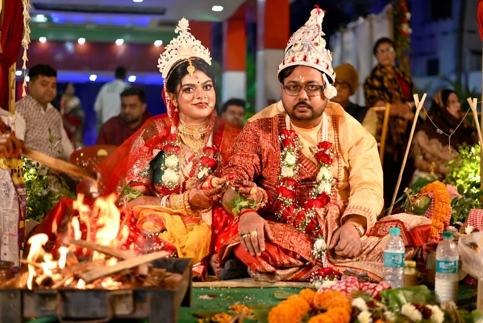 Bride and groom in vibrant attire during a traditional Indian wedding ceremony with fire rituals. - marriage ceremony celebration - Wedding dress and bridal accessory promo codes